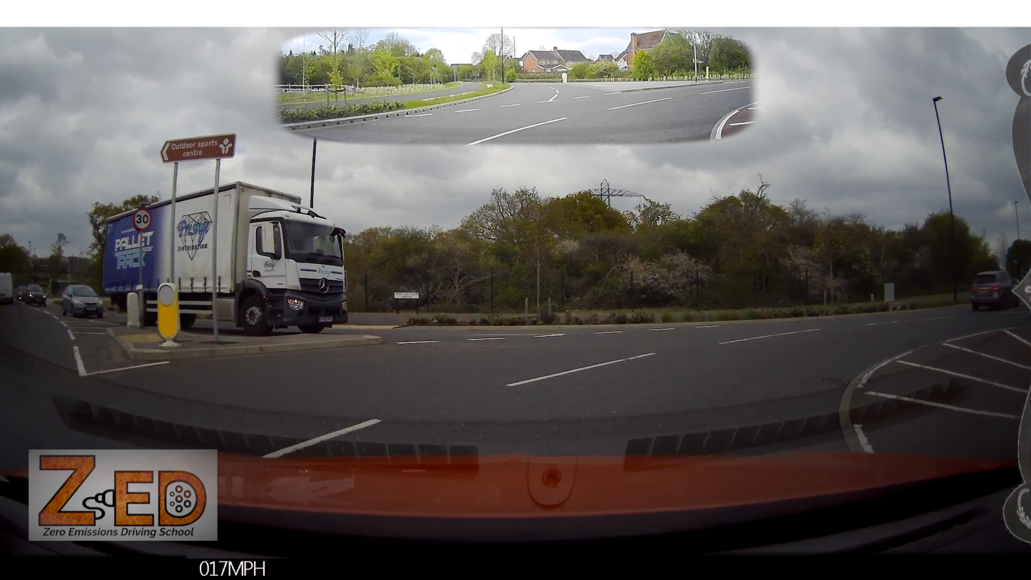 Truck on a road with a cloudy sky and trees in the background, featuring ZED driving school branding.