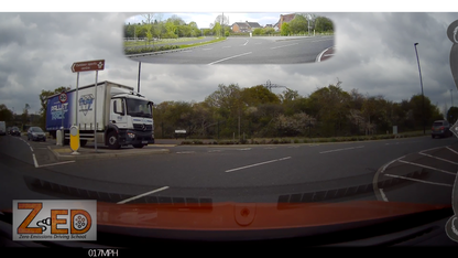 Truck on a road with a cloudy sky and trees in the background, featuring ZED driving school branding.