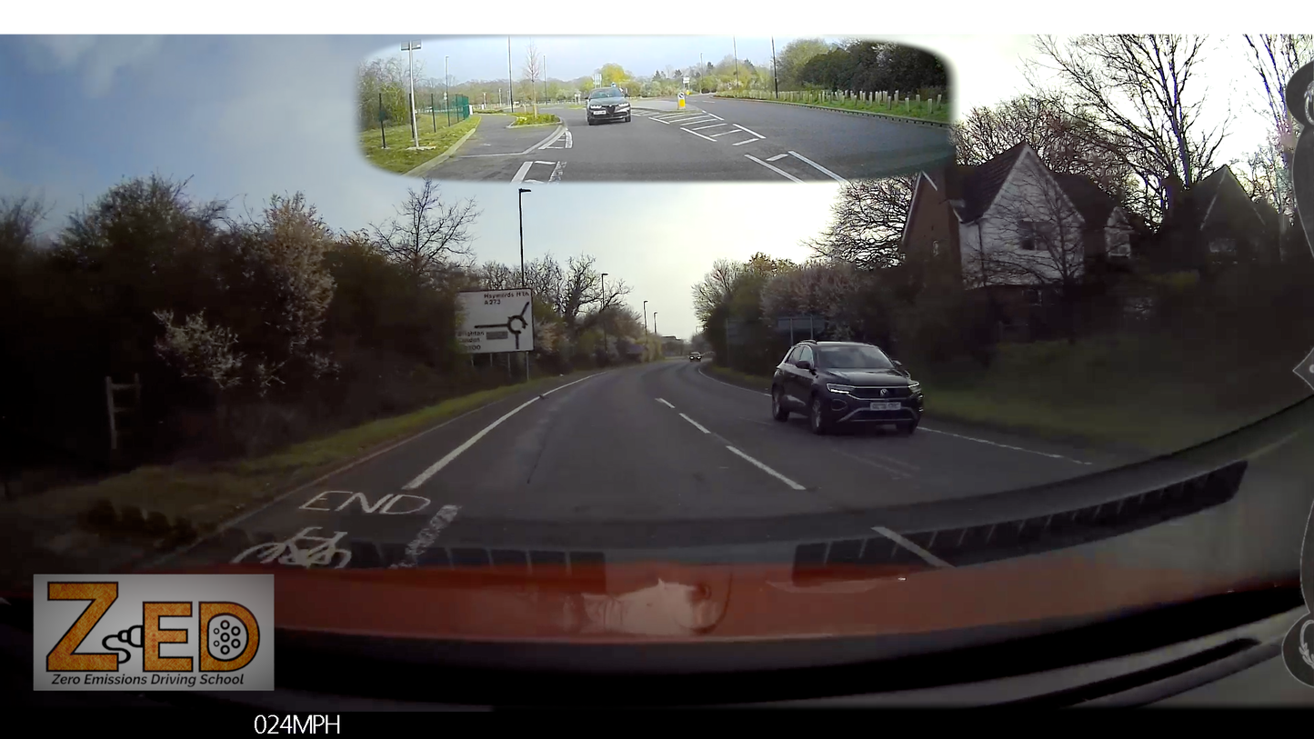 Car driving on a road with a split-screen showing a top-down view of the intersection.