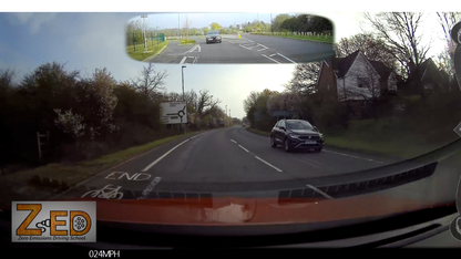 Car driving on a road with a split-screen showing a top-down view of the intersection.