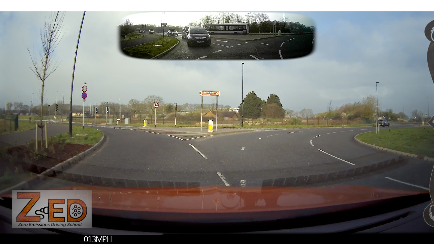 Car's rear view mirror showing a split-screen view of the road and a speedometer, with 'ZED' branding.