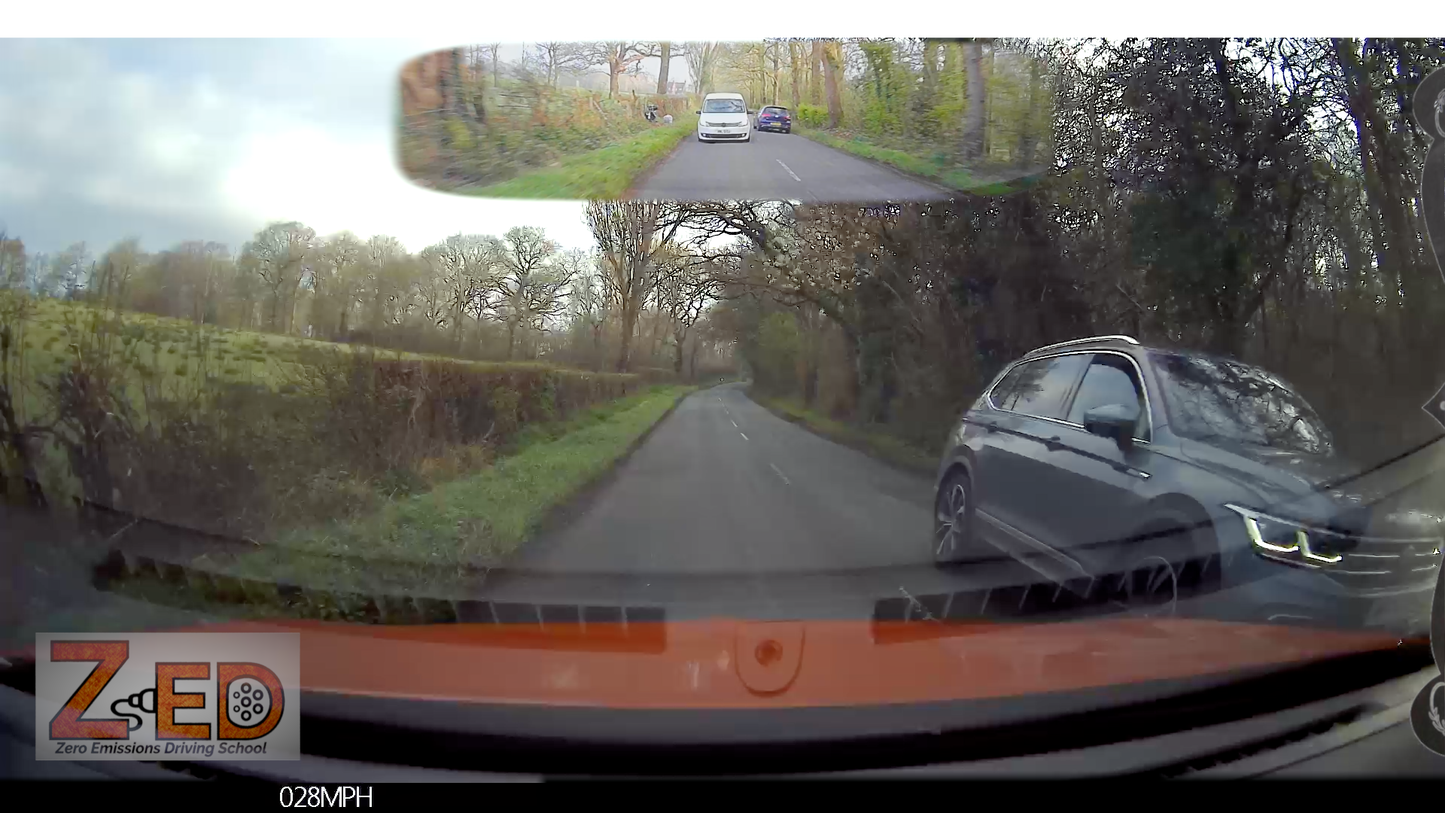Car dashboard with a rearview mirror displaying a wide-angle view of a road and surroundings.