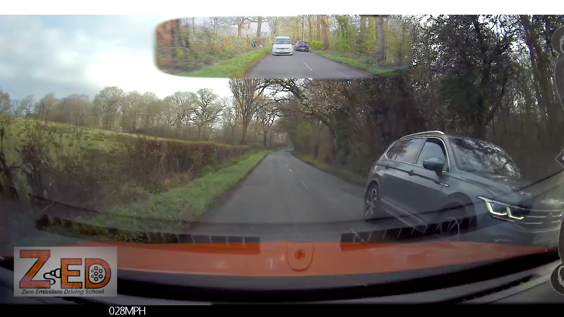 Car dashboard with a rearview mirror displaying a wide-angle view of a road and surroundings.