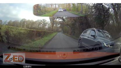 Car dashboard with a rearview mirror displaying a wide-angle view of a road and surroundings.