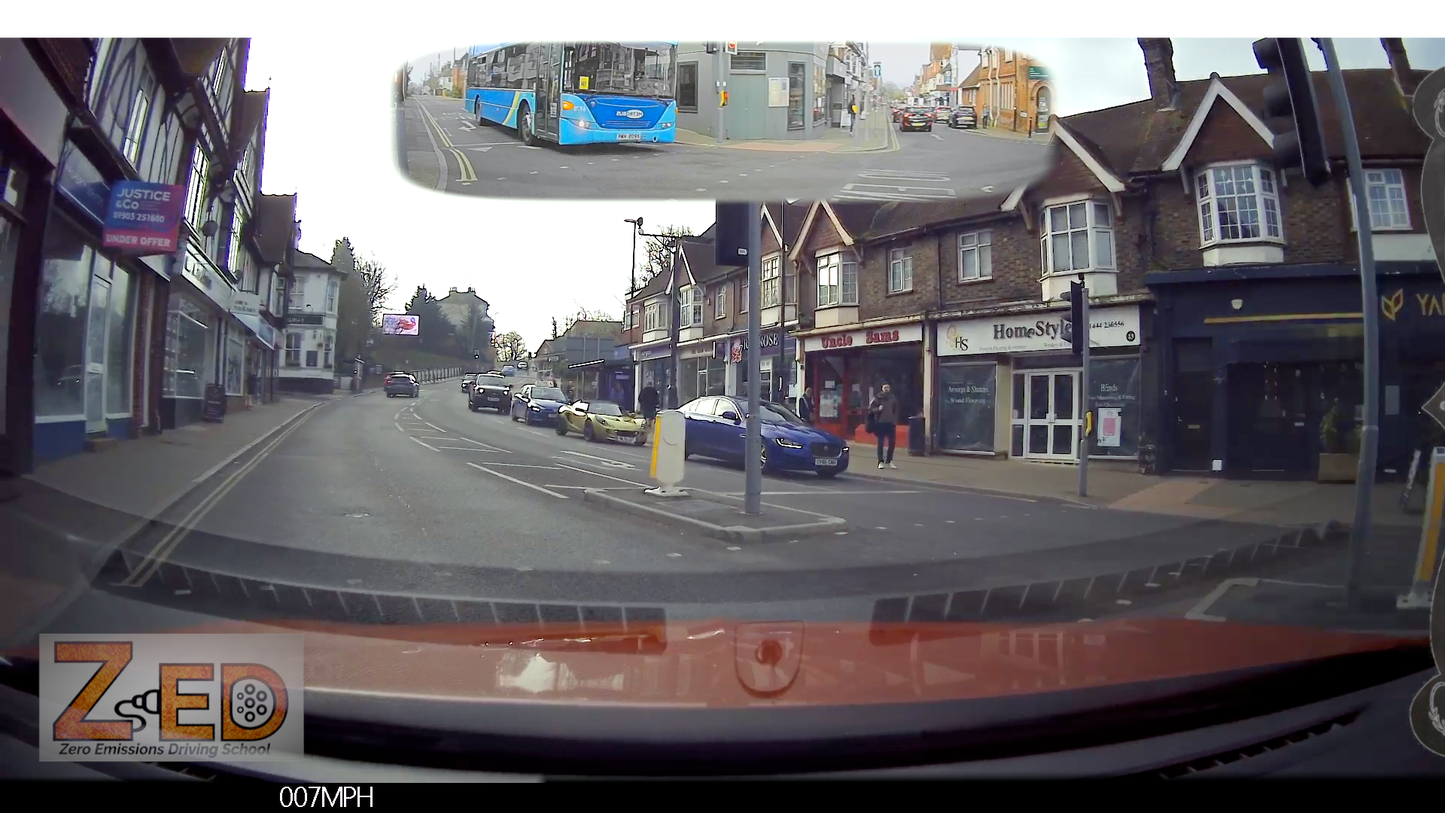 Dashcam view of a street with buildings and cars, including a ZED logo.